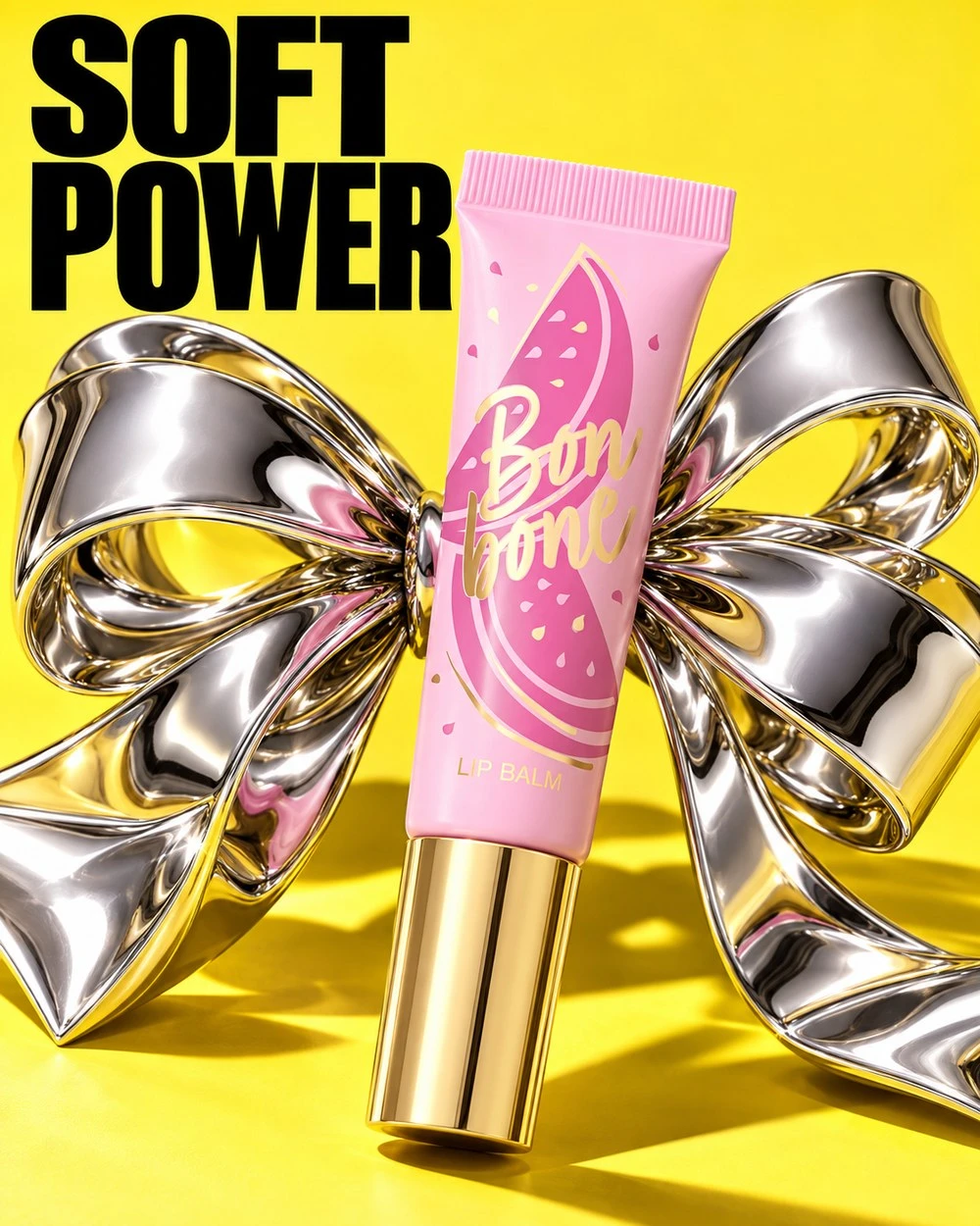 Lip balm ad on yellow: pink tube with watermelon print and a giant chrome bow, headline Soft power